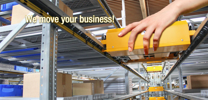 A human hand is moving a shuttle system in a warehouse.